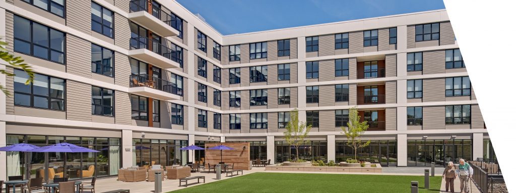 Exterior view of a senior living facility with outdoor seating