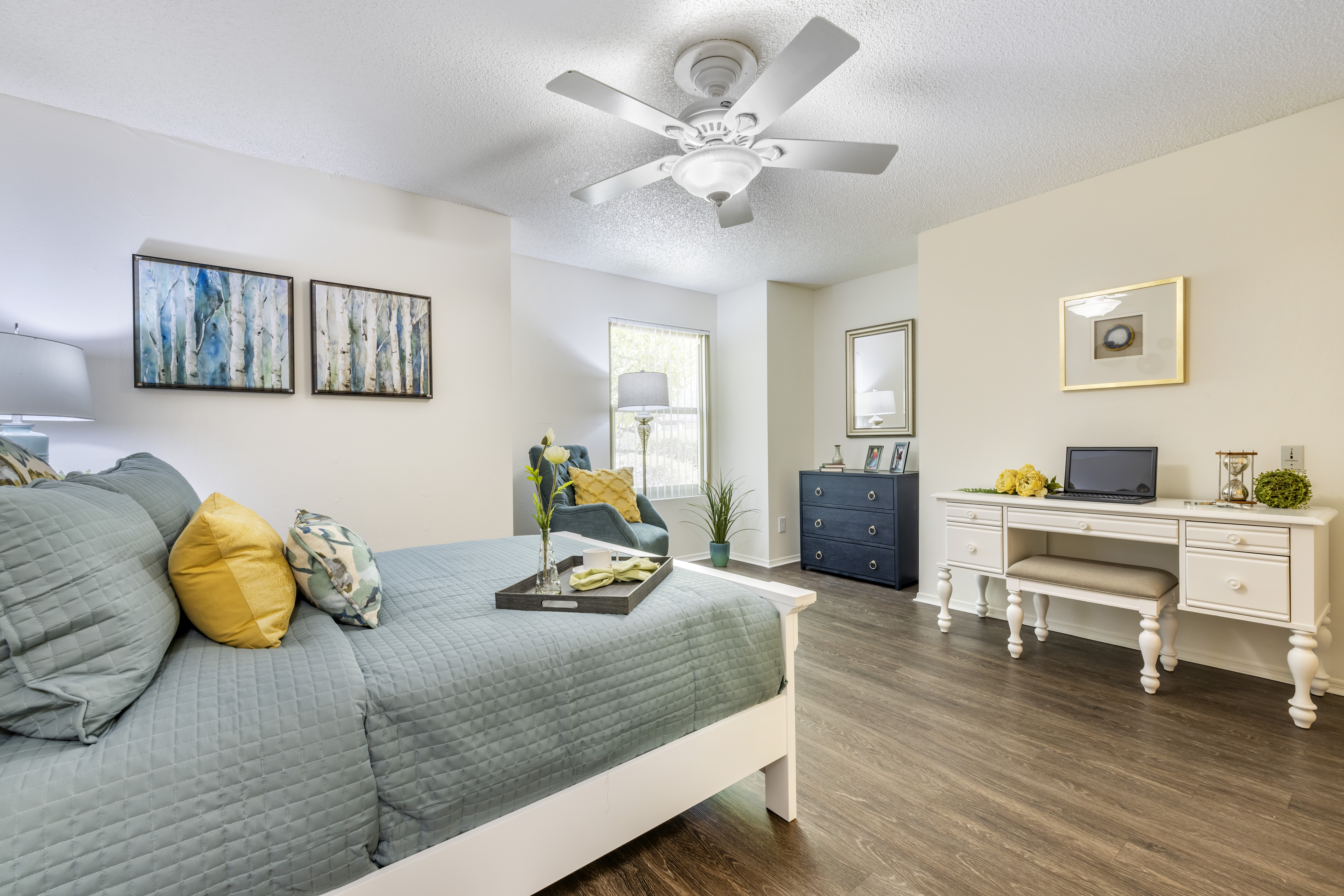 A cozy resident room with a bed, desk, and decor