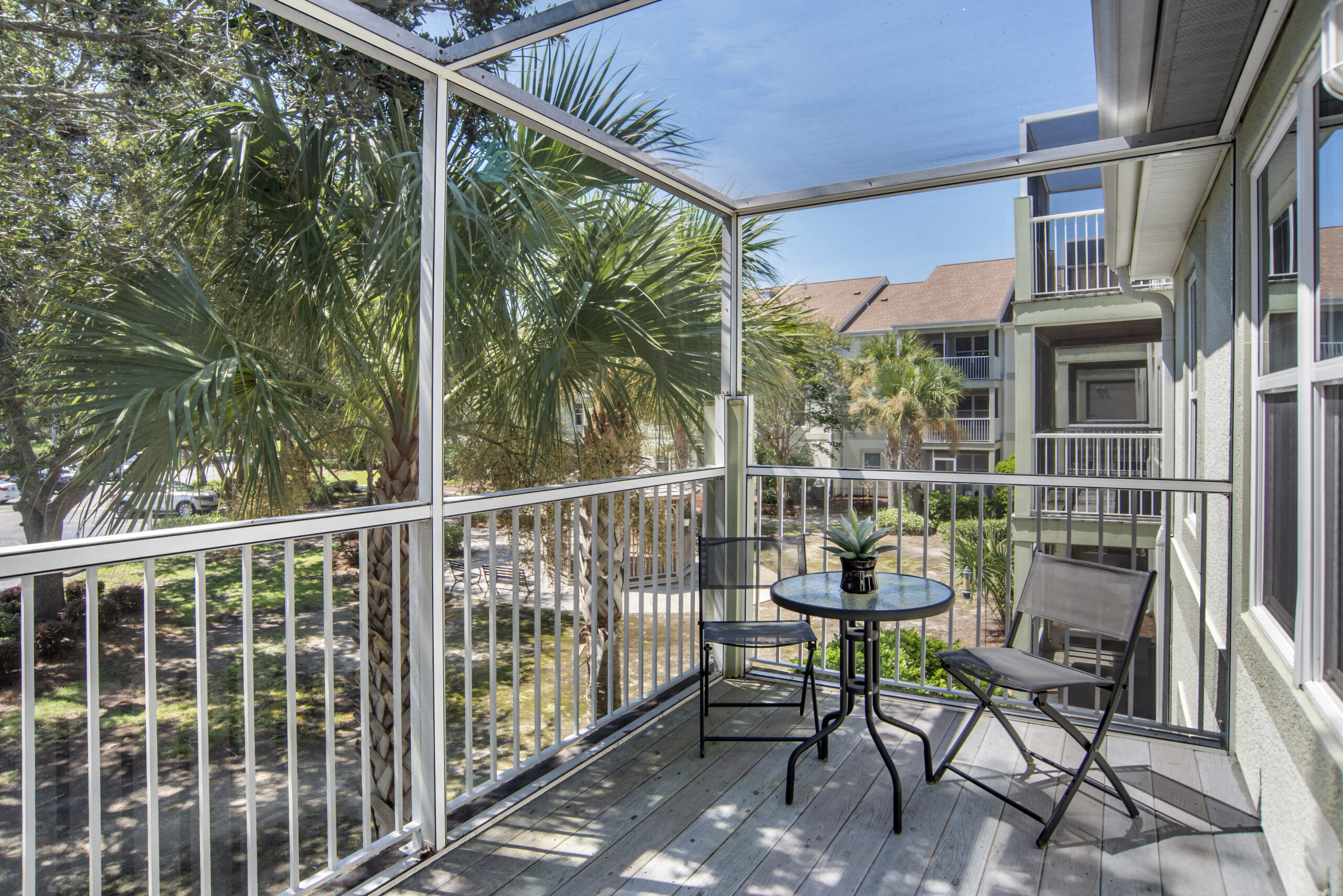 Balcony with a table and chairs overlooking palm trees