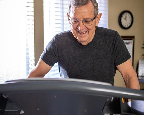 Elderly man smiling while using a treadmill