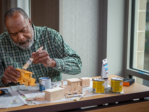 Resident crafting a wooden toy at a table