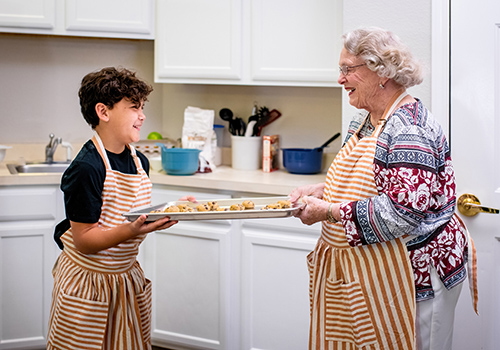 A resident baking cookies with a young volunteer in a kitchen