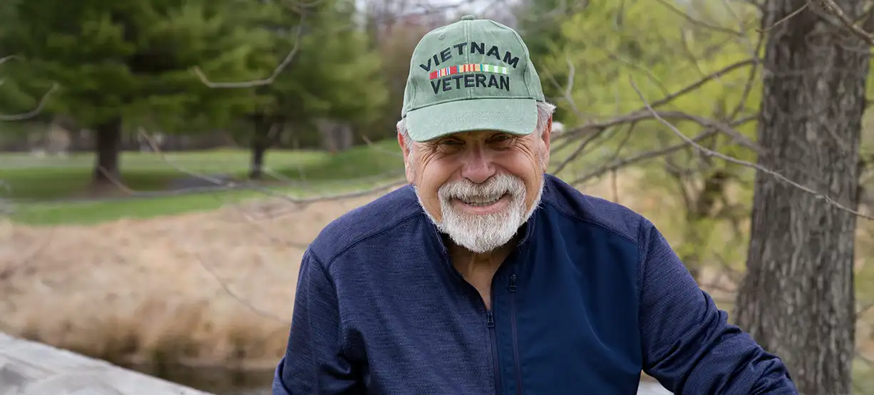 Smiling man in Vietnam veteran cap outdoors