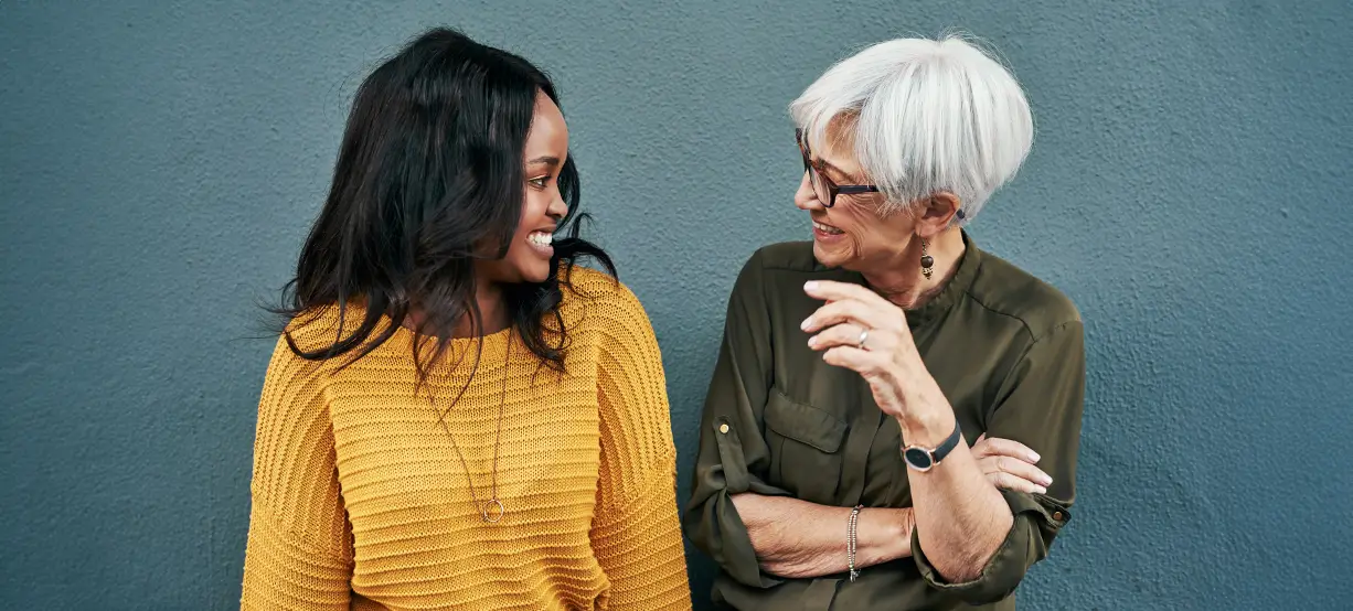 Two women laughing together in a friendly conversation.