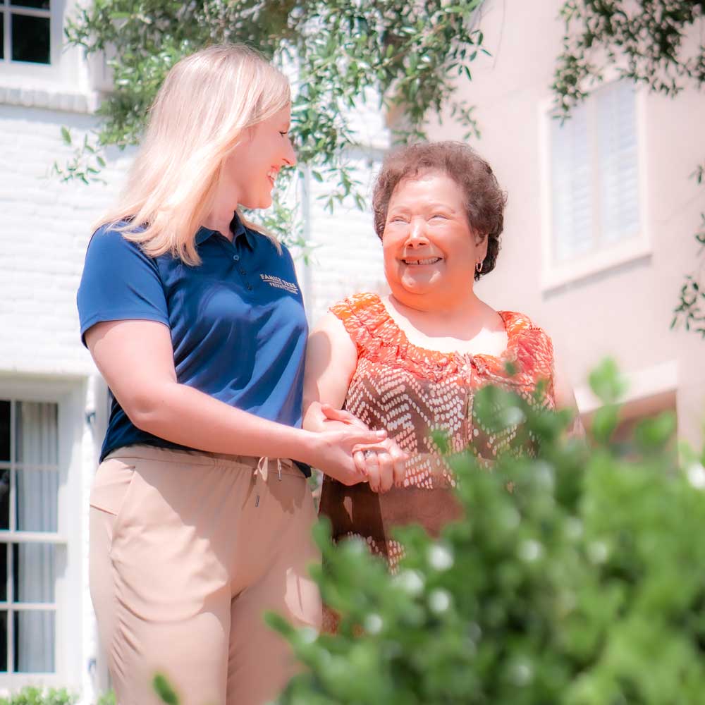 Staff member assisting a happy resident outdoors.