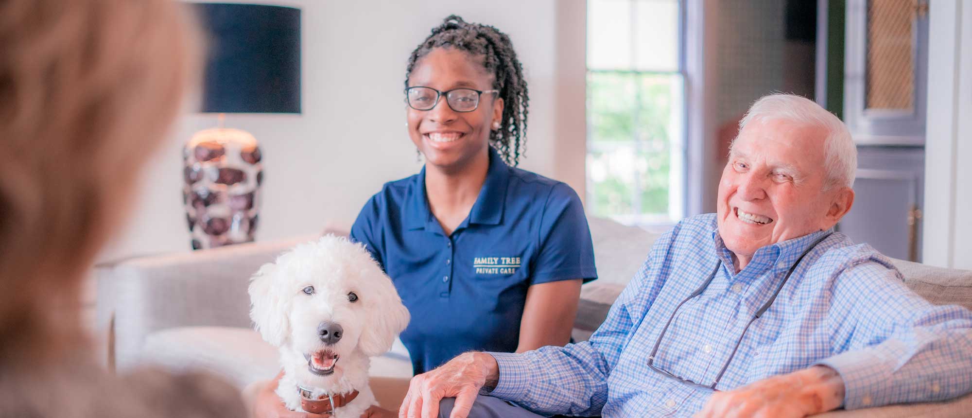 Resident and staff member with a dog in a cozy living area