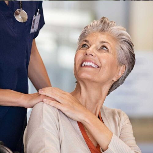 Smiling elderly woman with caregiver in common area