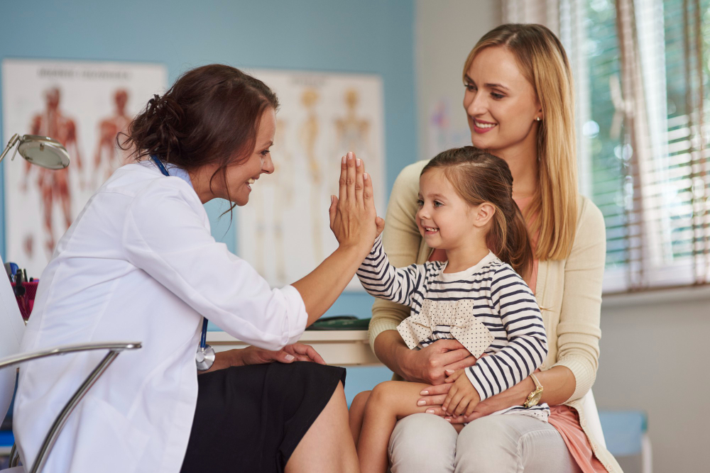 A doctor interacting with a mother and child in an office.