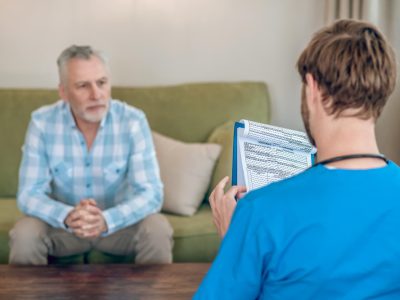 A staff member talks to a resident in a cozy living area.
