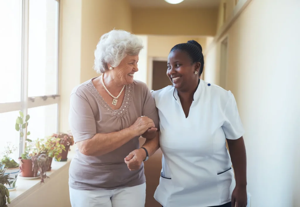 A caregiver and resident walking together in a hallway.
