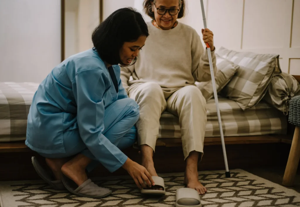 Caregiver assisting an elderly woman with shoes.