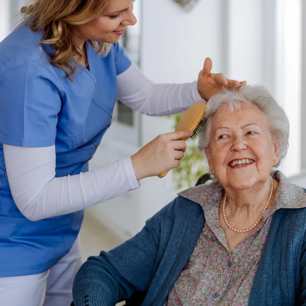 Caregiver brushing the hair of a smiling resident.