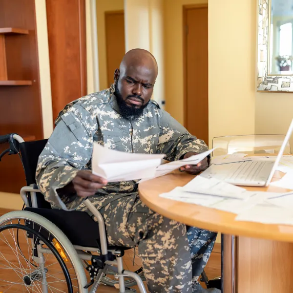 Man in wheelchair reading documents in an interior space.