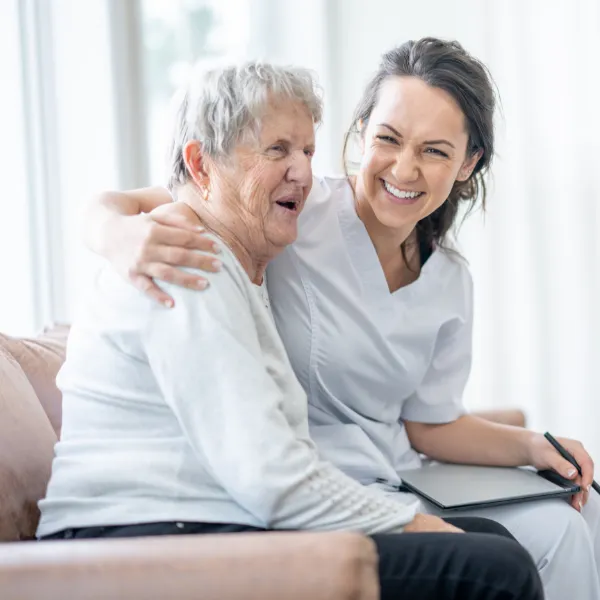 Smiling caregiver with elderly resident indoors