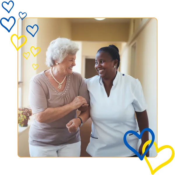 Caregiver and resident smiling together in a hallway