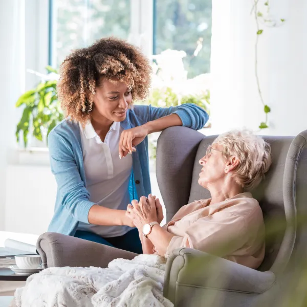 Staff interacting warmly with a resident indoors.