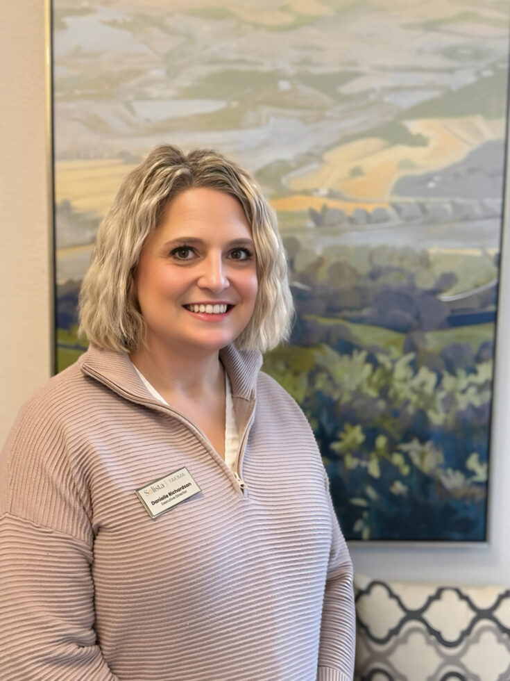Staff member posing in front of a painting.