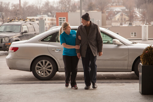 Staff assisting a resident near a car