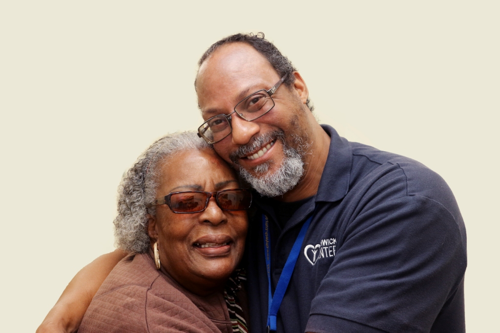 Staff member embracing a resident, both smiling.