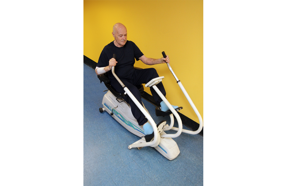 Resident exercising on fitness equipment indoors.