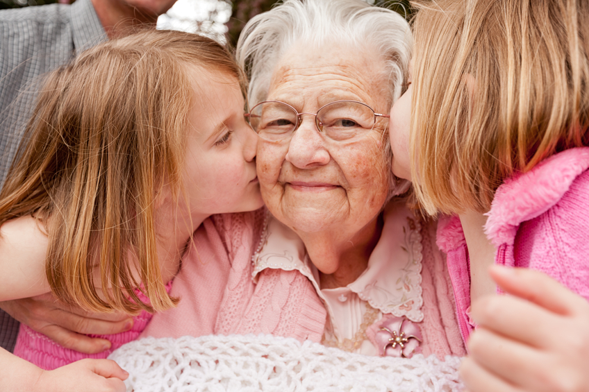 Elderly woman with two children, smiling together.
