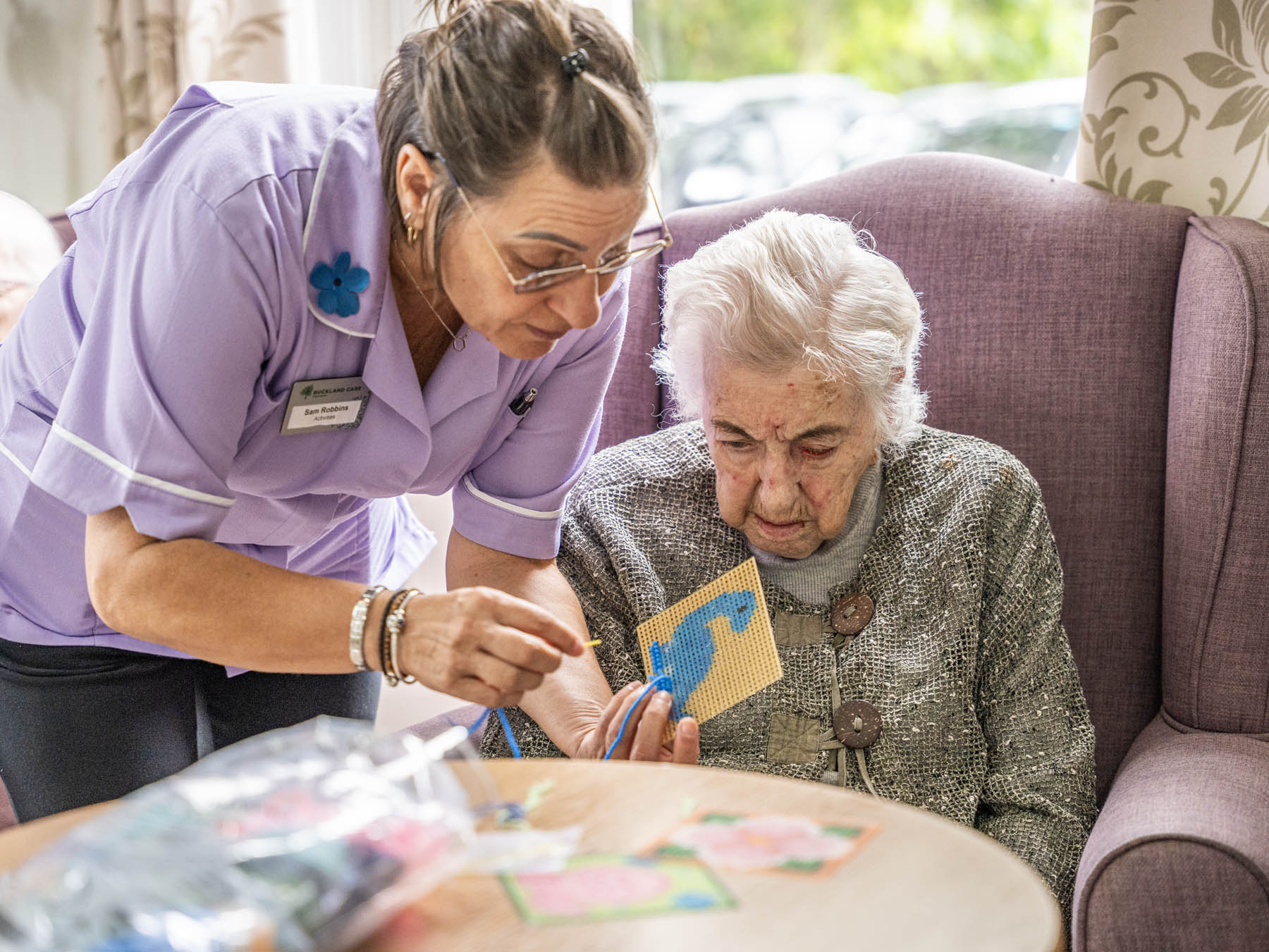 Staff assisting a resident with a craft activity