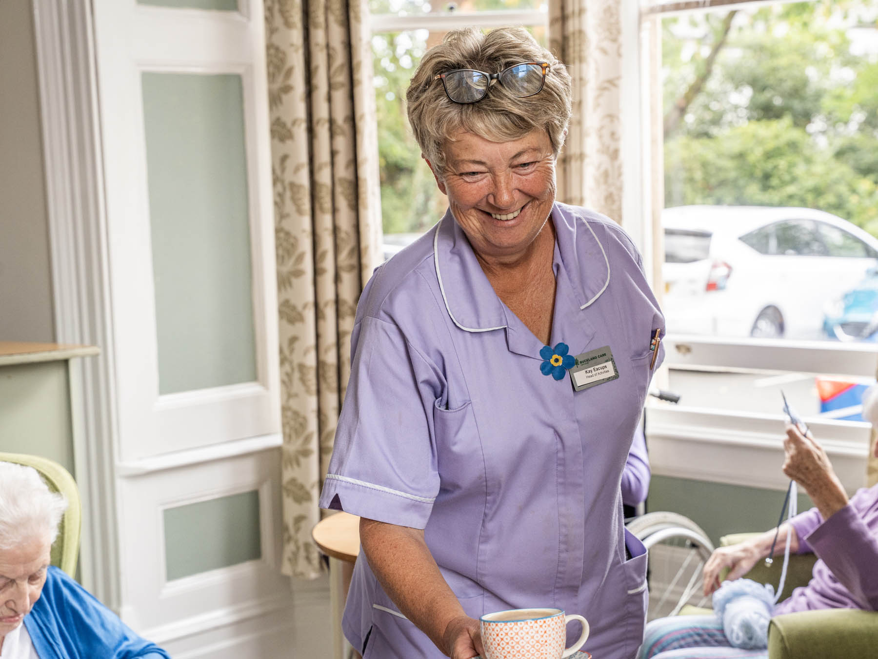Staff member serving tea to residents in a common area