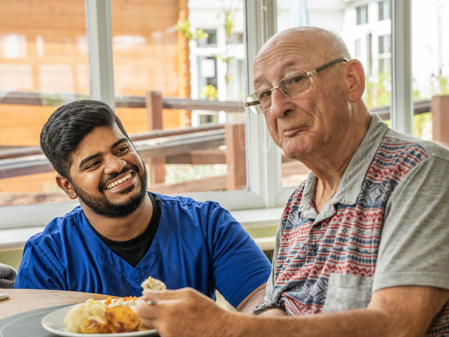 A caregiver and a resident sharing a meal
