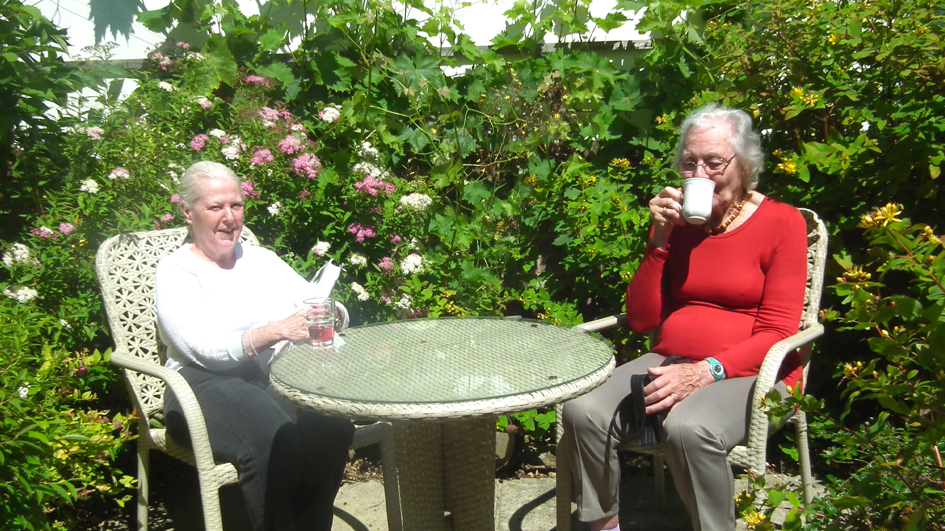 Two women enjoying drinks in a garden