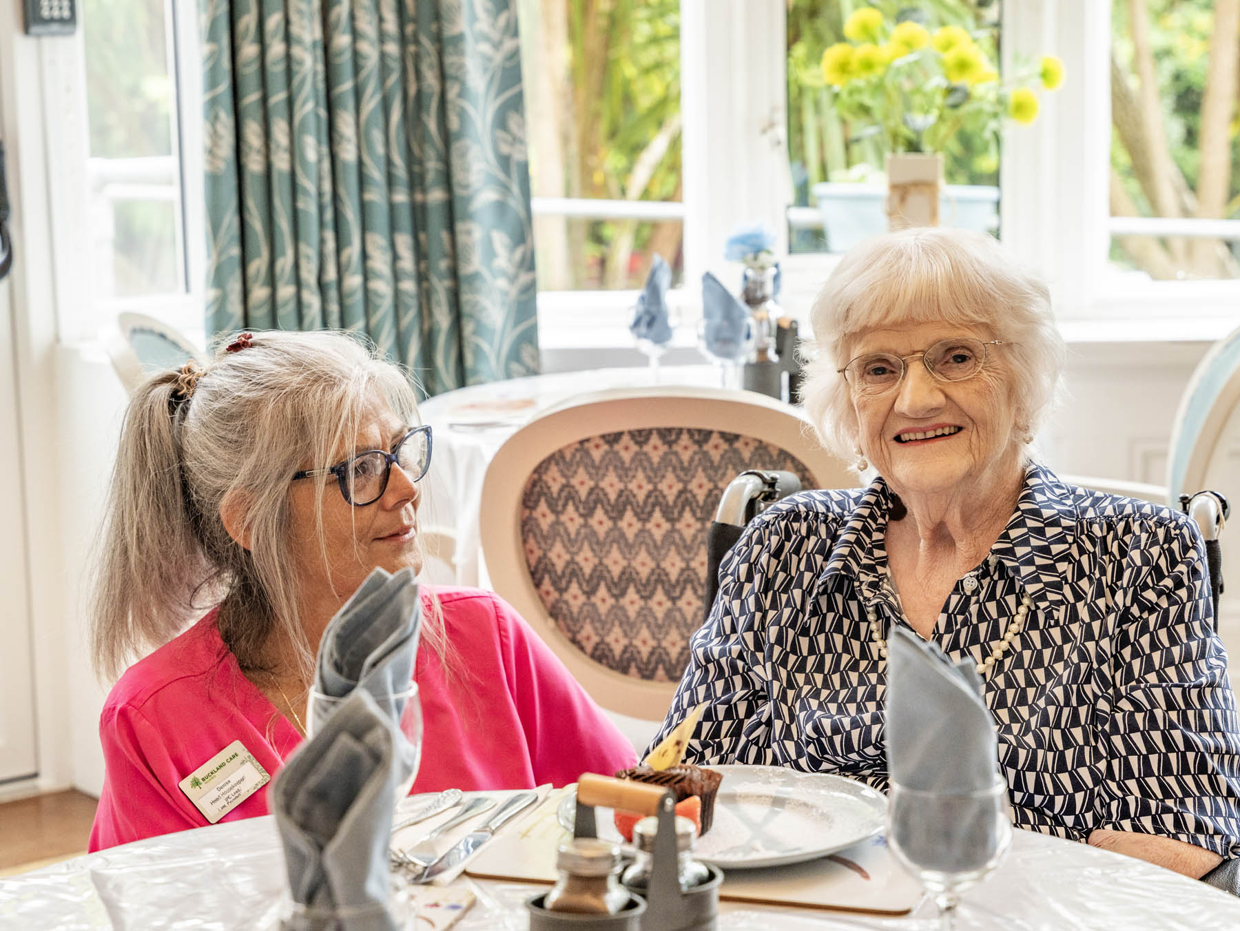 A resident smiling with staff in a bright room