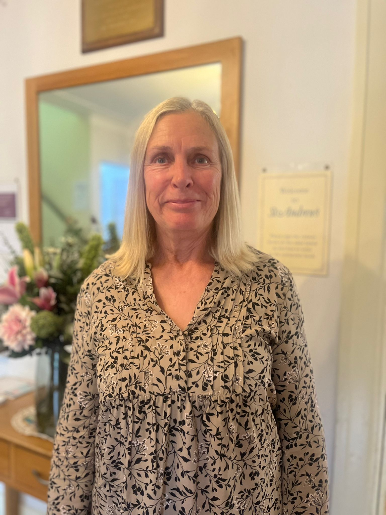 Staff member in a common area with flowers in the background