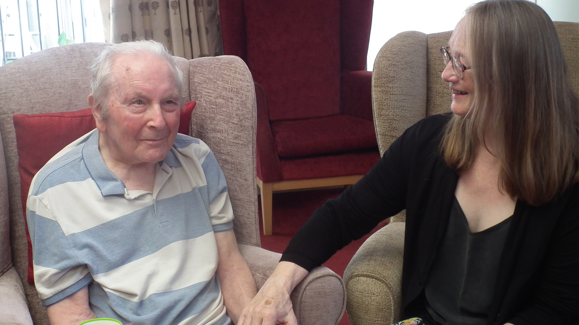 A resident and staff member sharing a moment in a cozy lounge