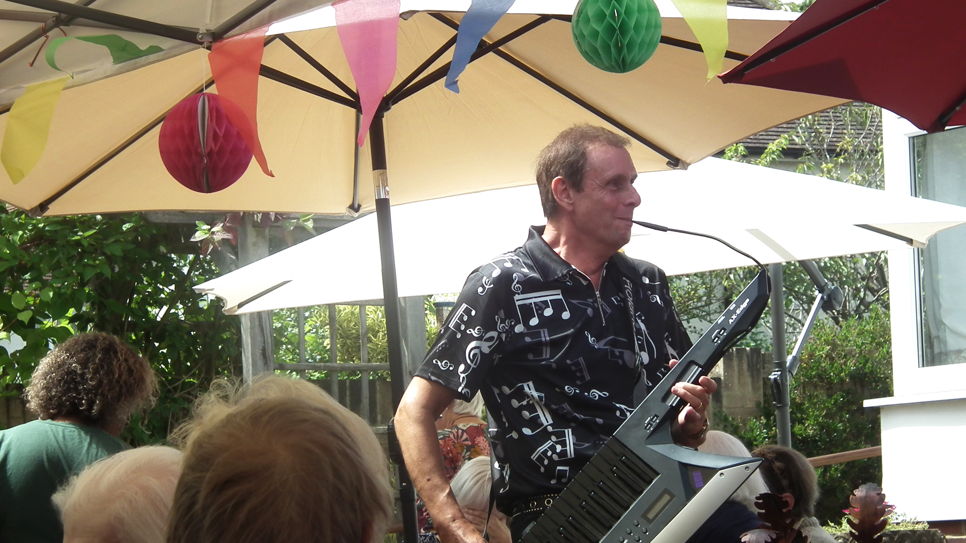 A musician performing outdoors with seniors enjoying the event