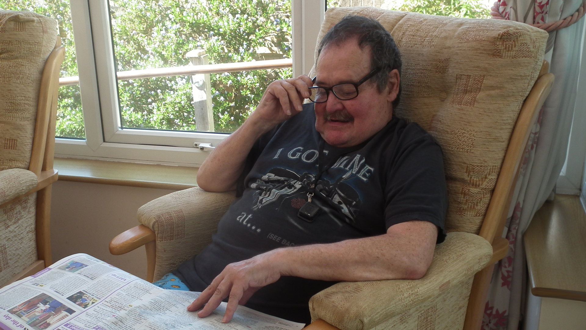Resident reading a newspaper in a bright lounge