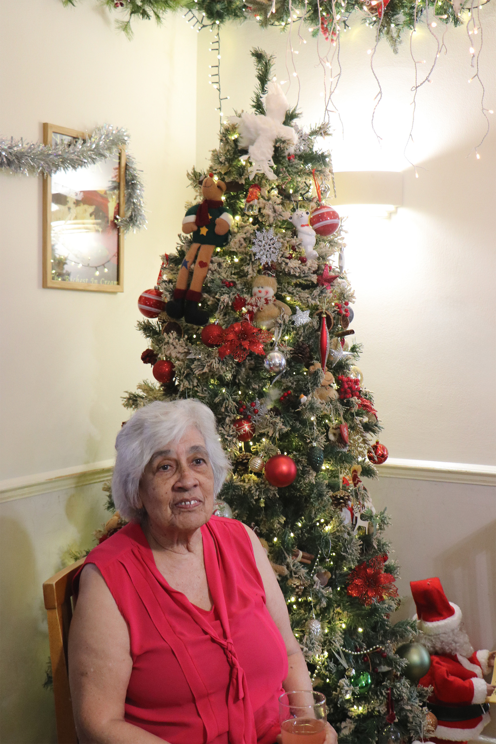 Resident enjoying the holiday season by a decorated Christmas tree