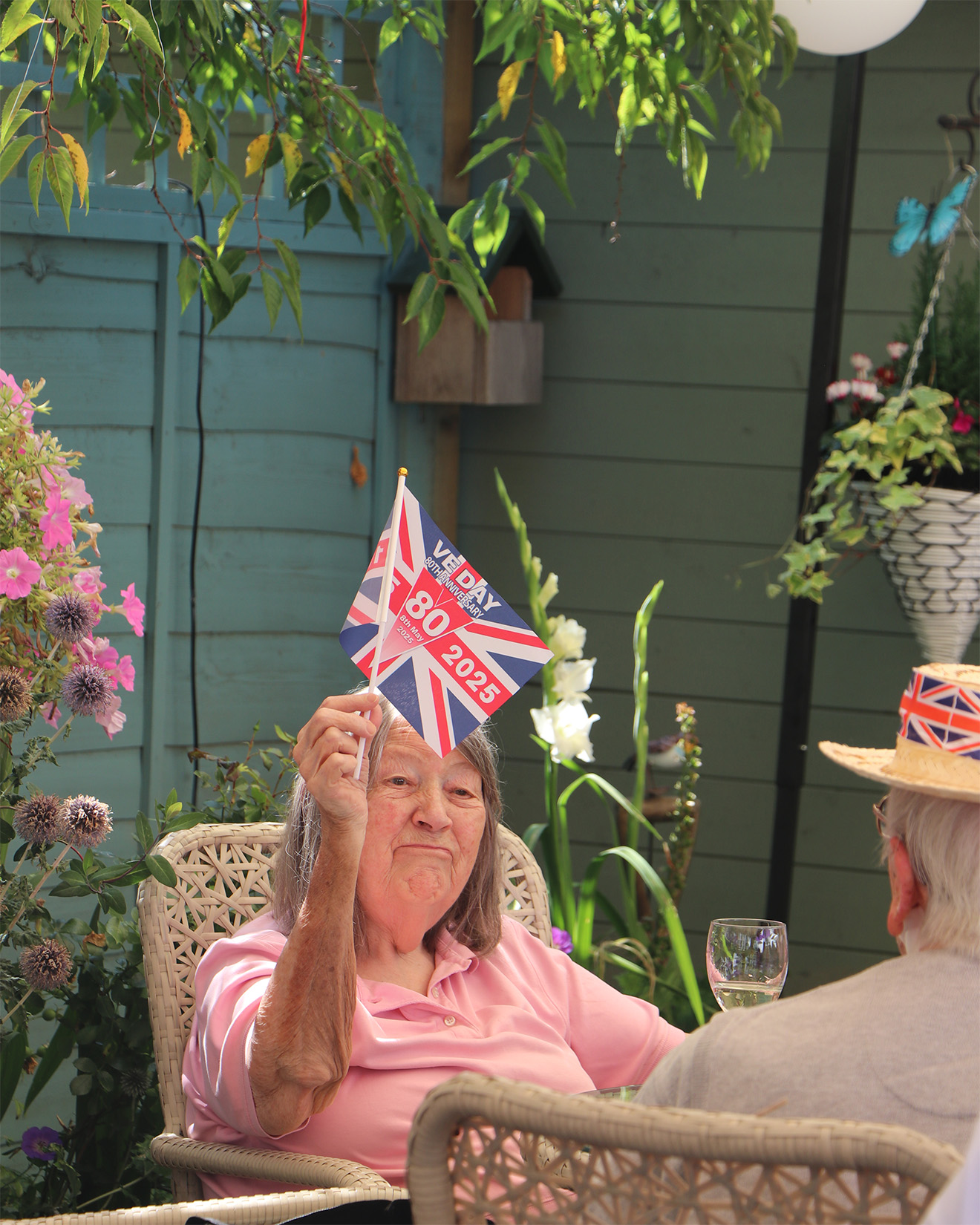 Elderly woman celebrating with a flag in a garden