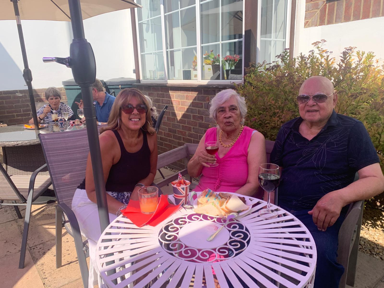 Three residents enjoying drinks in an outdoor seating area