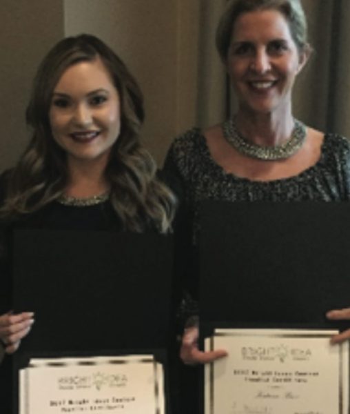 Two women holding certificates at an event