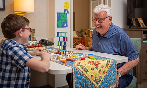 An elderly man playing with a child at a table