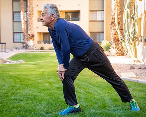 A man stretching in a grassy outdoor area