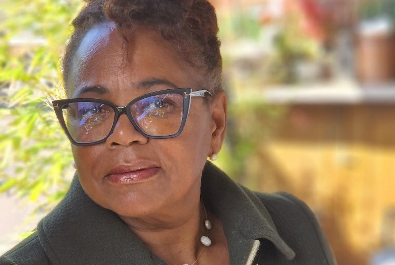 A friendly woman with glasses smiling outdoors
