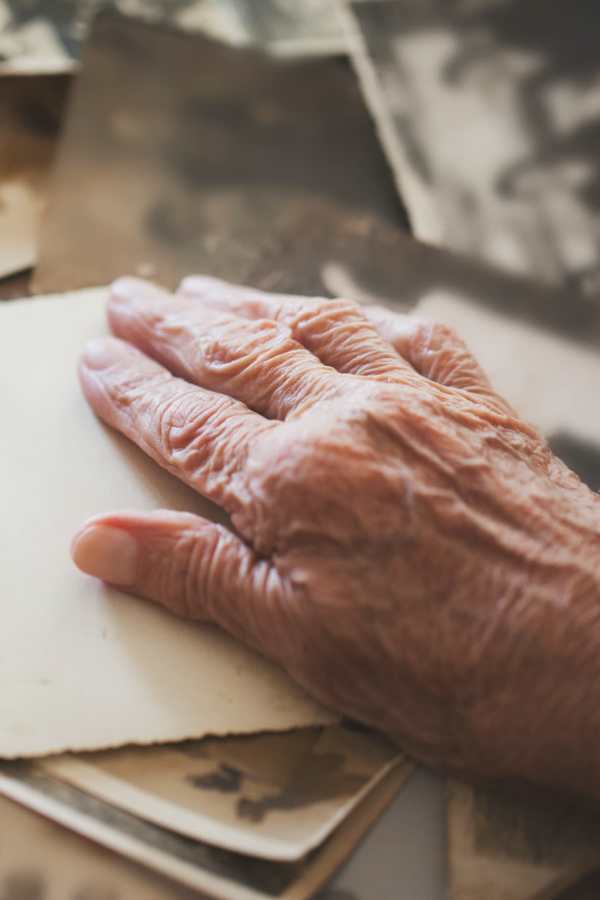 An elderly hand resting on gray photographs
