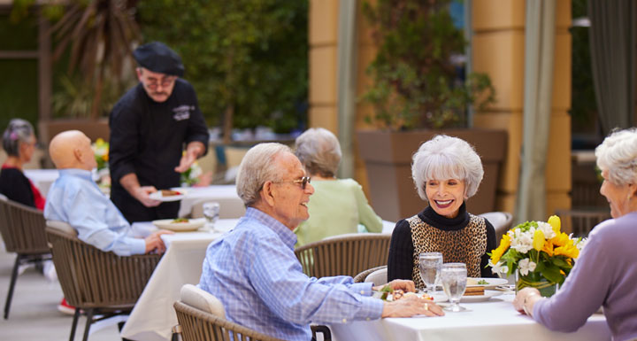 Residents enjoying meals outdoors at a dining table