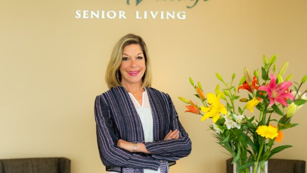 A staff member smiling in a well-lit lobby with flowers