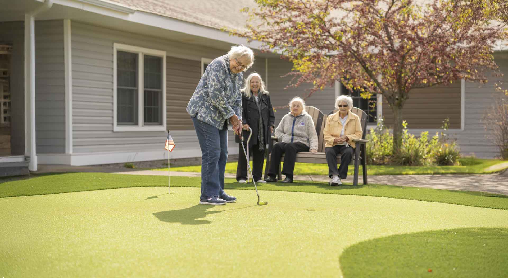 Resident practicing golf on a putting green outdoors