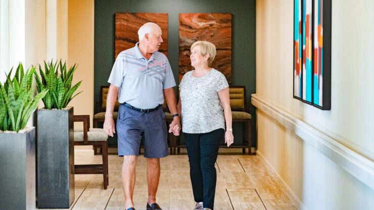 Couple walking hand in hand in a facility hallway