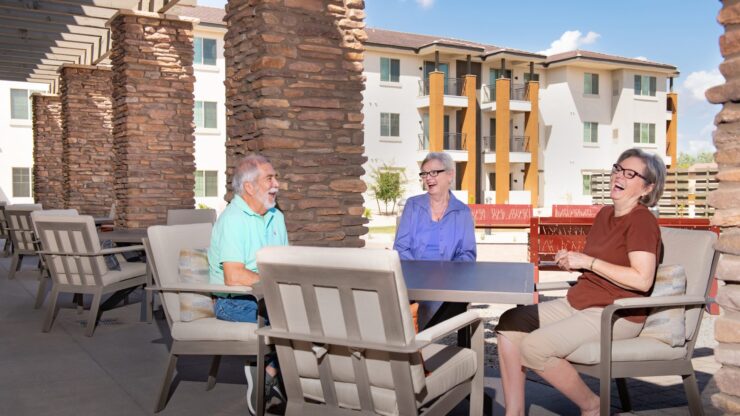 Three residents laughing together on a patio