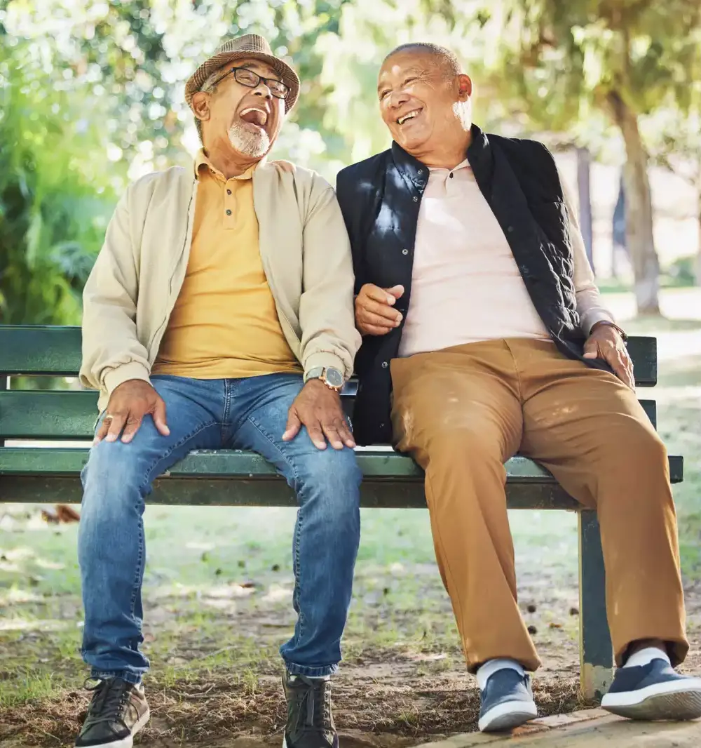Two senior men laughing on a park bench