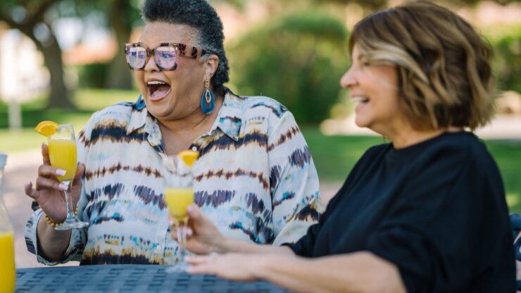 Two women enjoying drinks outdoors in a garden setting