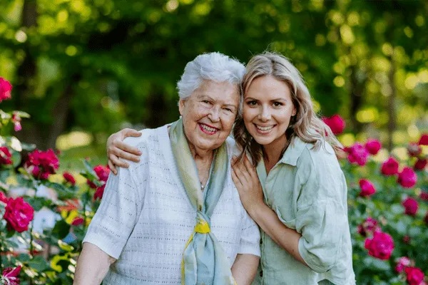 Senior resident and staff member smiling in a garden